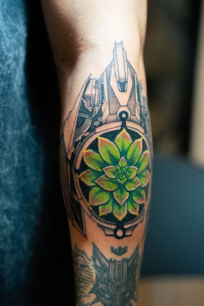 Geometrische mandalatattoo met een groene bloem in het midden op een onderbeen
