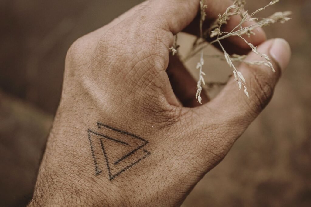 Klein driehoekje als minimalistische tattoo op de rug van een hand